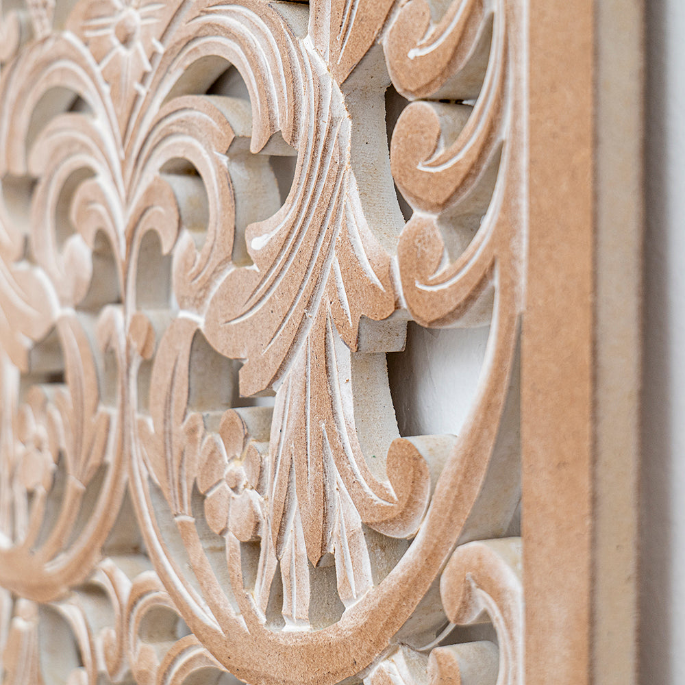 Close-up of an ornate carved decorative panel with swirling acanthus leaf motifs in a light beige stone or wood finish.