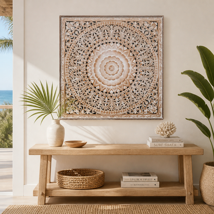 A square carved wooden wall art piece with an intricate mandala pattern, styled in a bright, modern boho living room above a wooden console table.