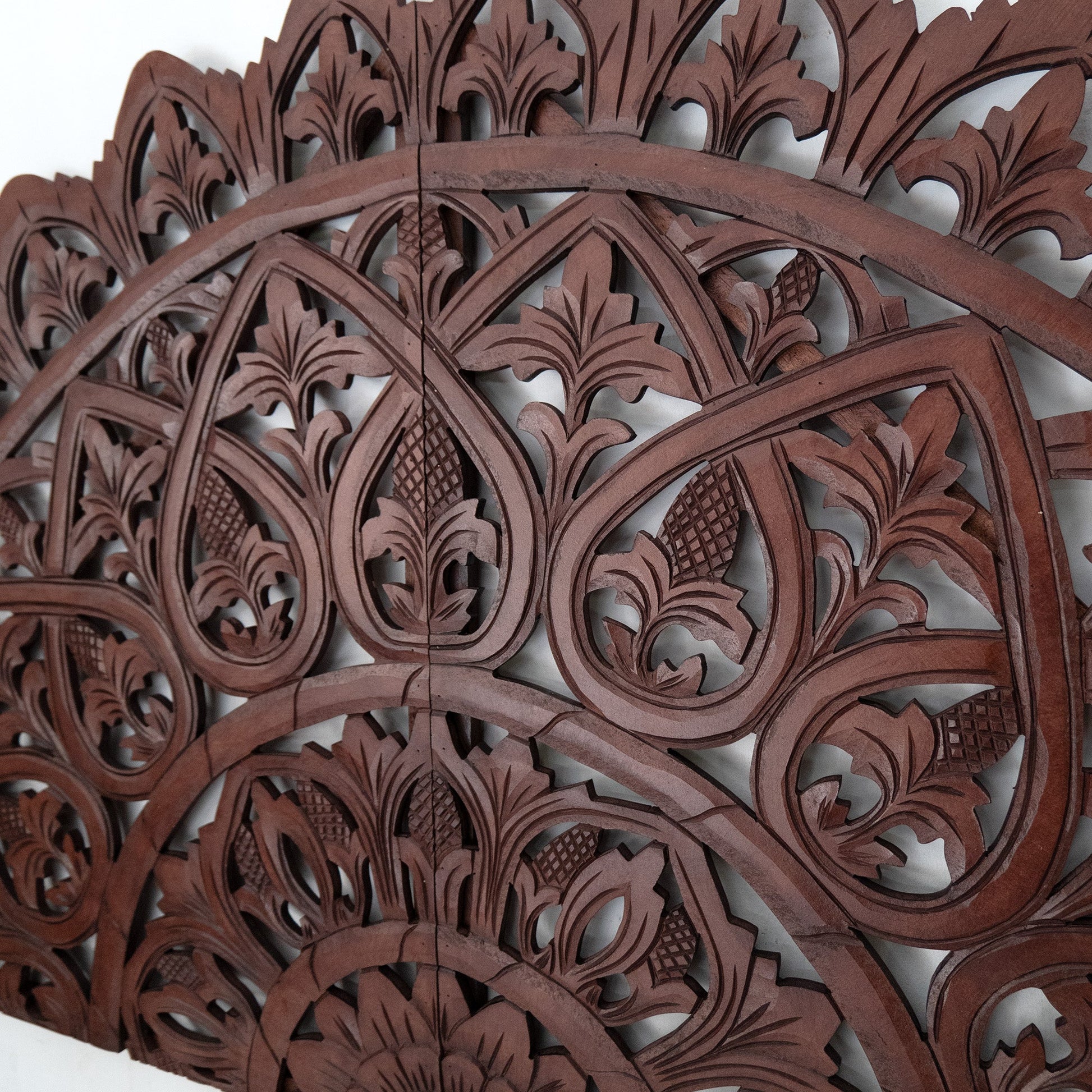 Close-up of a wooden wall panel with intricate carvings on a white background